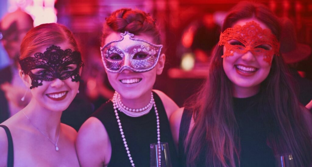 group of three women wearing masquerade masks at a private event
